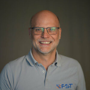 Michael Wensing im grauen Polo-Shirt mit FST-Logo.