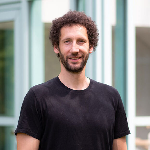Sebastian Rauch im schwarzen Shirt, mit braunen Haaren und Vollbart.